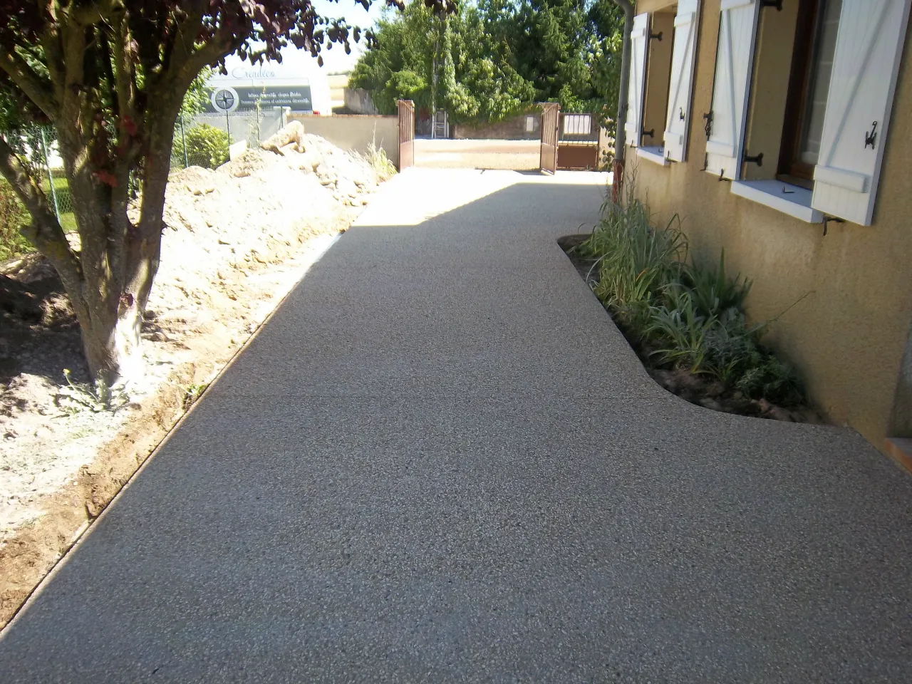 Longue allée en béton désactivé bordée de massifs